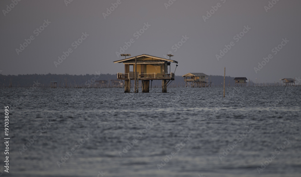 Wooden yellow house in the sea at sunset time