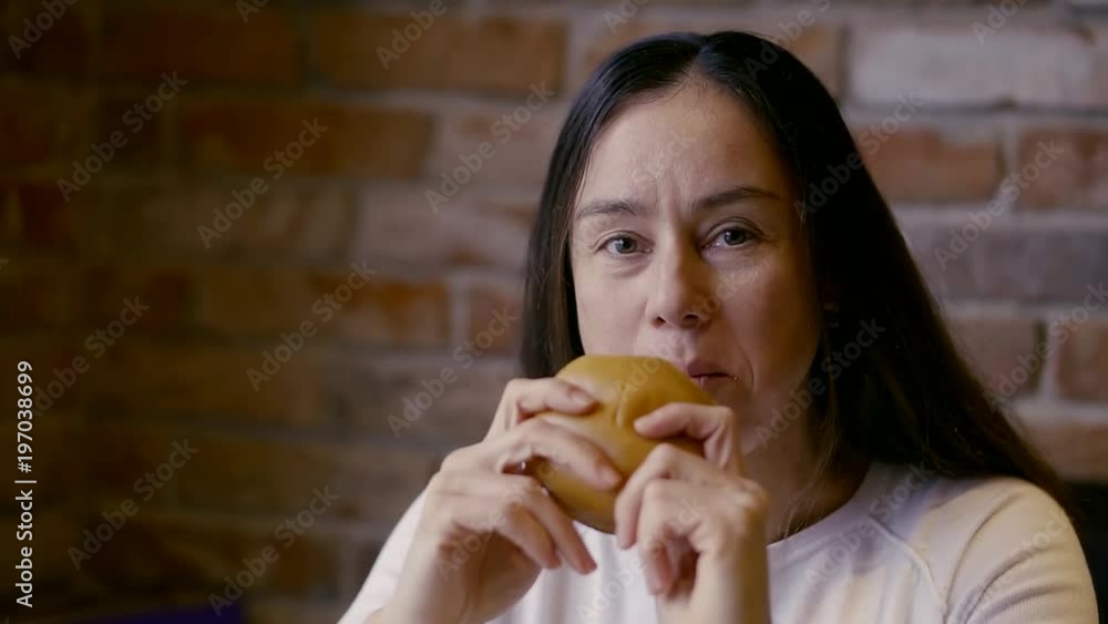 Close-up of Burger with a fish in the hands of women. Girl biting a chunk and chewing. Close-up of Burger with a fish in the hands of women. Girl biting a chunk and chewing.