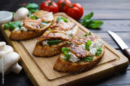 Tasty Italian bruschetta with grilled chicken, ricotta and basil, healthy and delicious snack close up