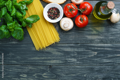 Pasta ingredients. Raw spaghetti, tomatoes, basil, olive oil, mushrooms and spices on wooden table, flat lay. Italian cuisine food background concept