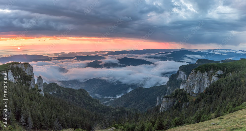 Panorama of a beautiful mountain view with fog over the peaks at sunrise, Ceahlau massif, Eastern Carpathians, Moldova, Romania