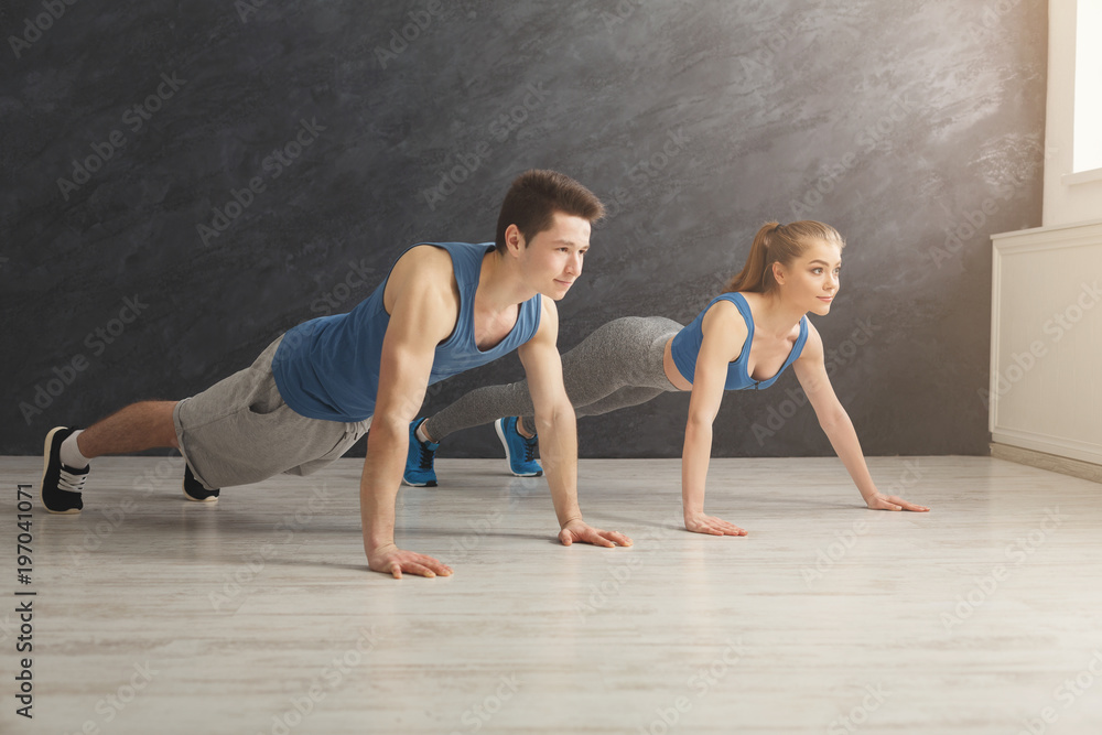 Couple making plank or push ups exercise indoors Couple making plank or push ups exercise indoors