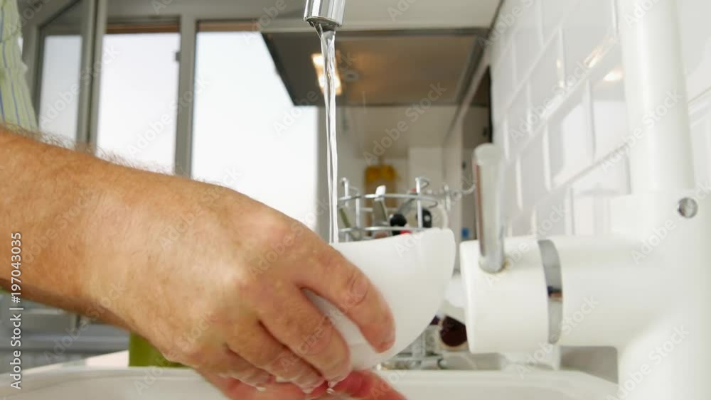 Man in Kitchen Washing Dishes in the Sink with Water Jet Man in Kitchen Washing Dishes in the Sink with Water Jet