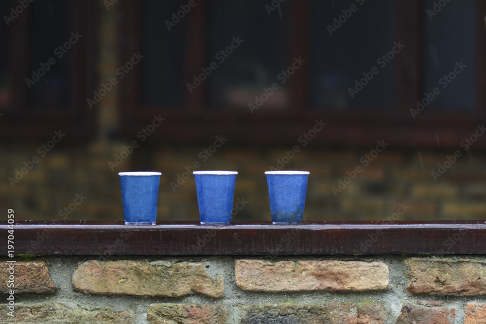 tree paper cups on a bar, under the rain against blurry background.