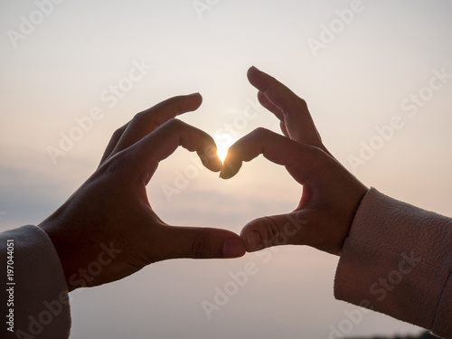 The hand of the couple is heart shaped..Along the background of the sky And the sun