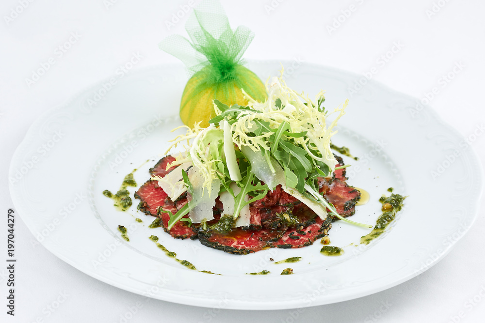 Delicious meal. Tasty carpaccio of meat with few kinds of cheese, green leaves of arugula and lemon. Delicious meal. Tasty carpaccio of meat with few kinds of cheese, green leaves of arugula and lemon.