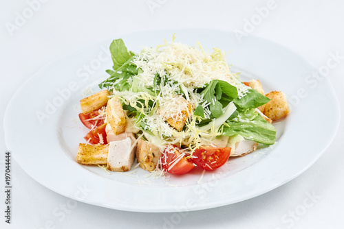 Delicious fresh caesar salad. Caesar salad with cheese, chicken, tomatoes, rusks and green leaves of arugula.