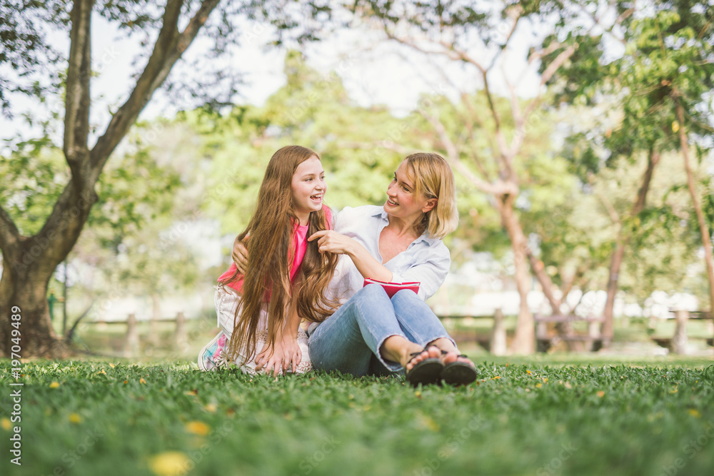 Fototapeta premium mom and daughter reading book in park