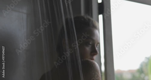 handsome young sexy woman or girl standing in the bathroom in fromt of opened window, taking shower, looking outside photo