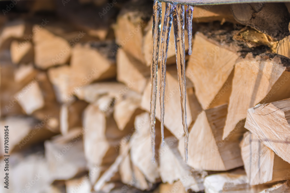 Eiszapfen vor gespaltenem Brennholz im Winter