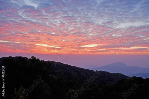 Sun rise purple orange sky background with landscape of mountain and tree with cloudy sky