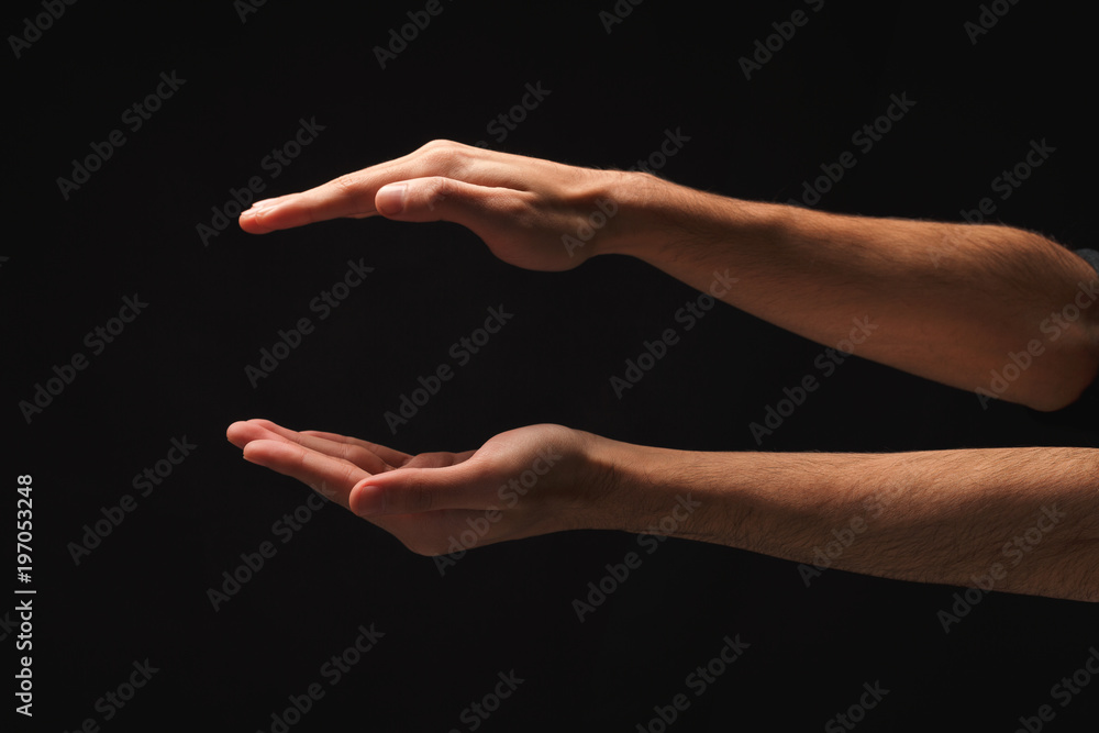 Male hands measuring something on black background