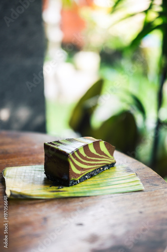Raw mint chocolate spiral mousse cake on a leaf. Green nature background. Gluten-free, wheat-free, dairy-free, sugar-free dessert. Copyspace