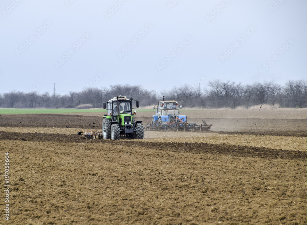 Lush and loosen the soil on the field before sowing. The tractor plows a field with a plow Lush and loosen the soil on the field before sowing. The tractor plows a field with a plow