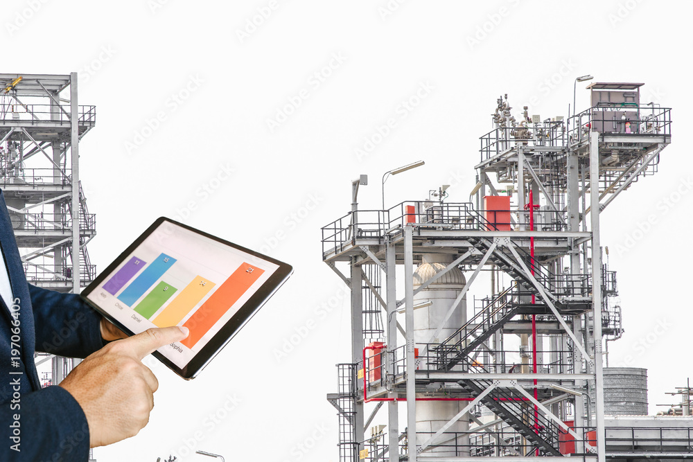 businessman fingers touching chart tablet against oil refinery in petrochemical Aerial view oil refinery night during twilight,Industrial zone,Energy power station 