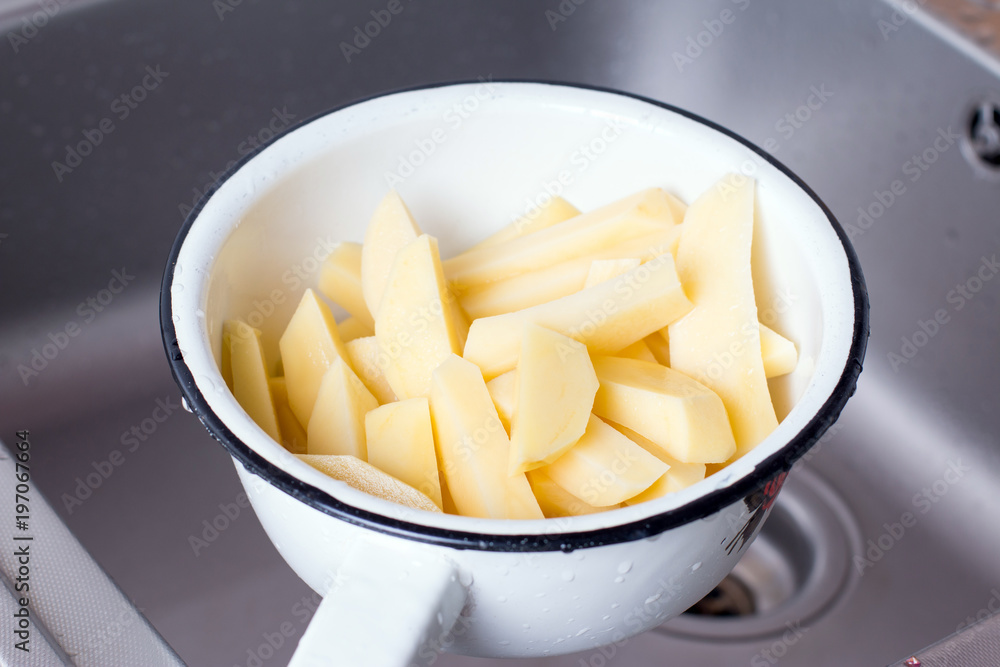 Draining boiled potato slices in colander Draining boiled potato slices in colander