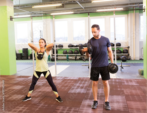 man and woman with kettlebell exercising in gym