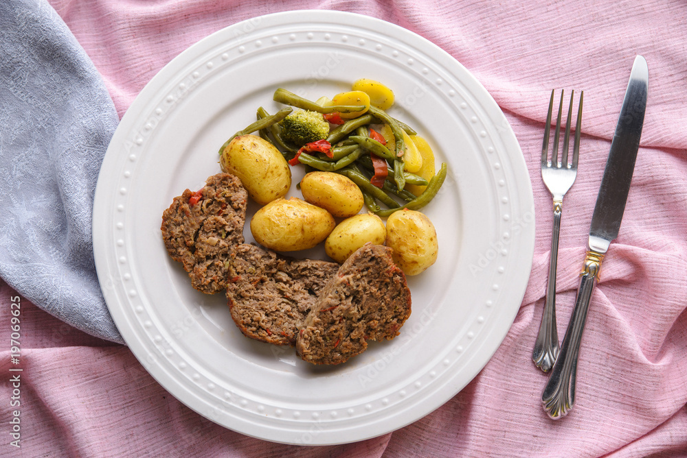 Meatloaf, potatoes and vegetables on a white plate