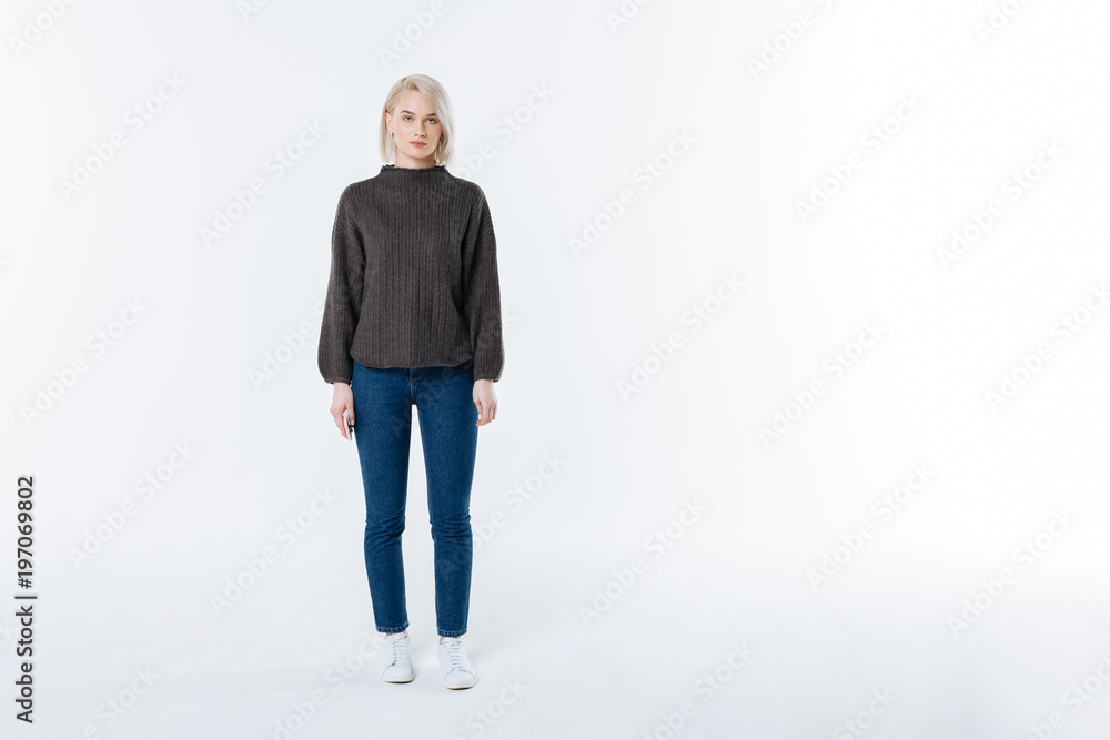 Serious look. Nice pleasant young woman standing against the white background and looking at you while wearing casual clothes Serious look. Nice pleasant young woman standing against the white background and looking at you while wearing casual clothes