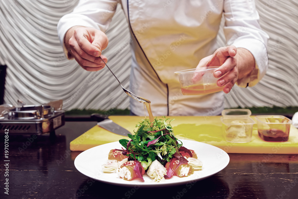 Chef is pouring sauce on appetizer, toned