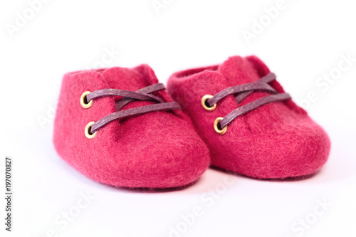 Pink handmade baby shoes made of merino wool on a white background.