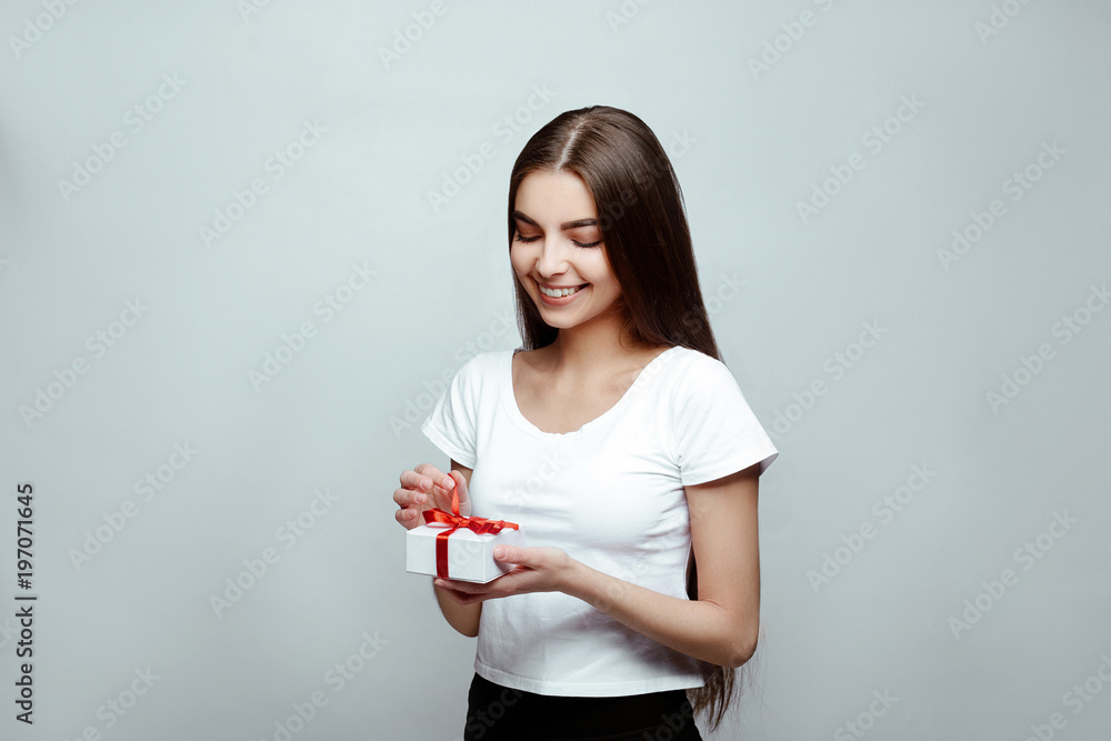 human emotions. Portrait of the young beautiful woman brunette with long dark brilliant hair. The girl poses on a white background, sincere smiles and unwraps the gift human emotions. Portrait of the young beautiful woman brunette with long dark brilliant hair. The girl poses on a white background, sincere smiles and unwraps the gift