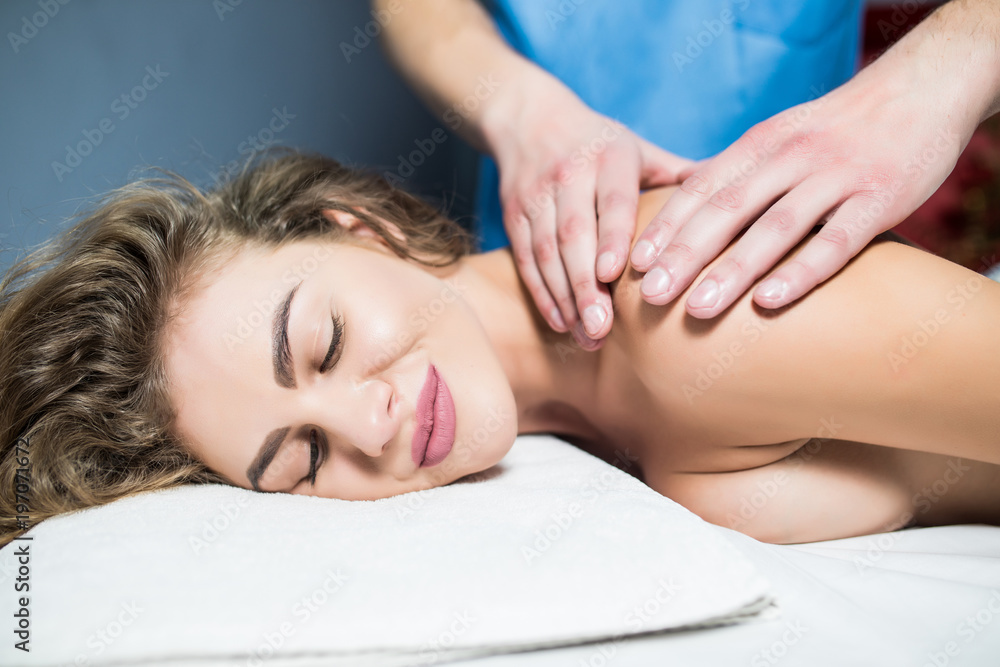 Young beautiful girl lying on massage table and enjoying massage in spa Young beautiful girl lying on massage table and enjoying massage in spa