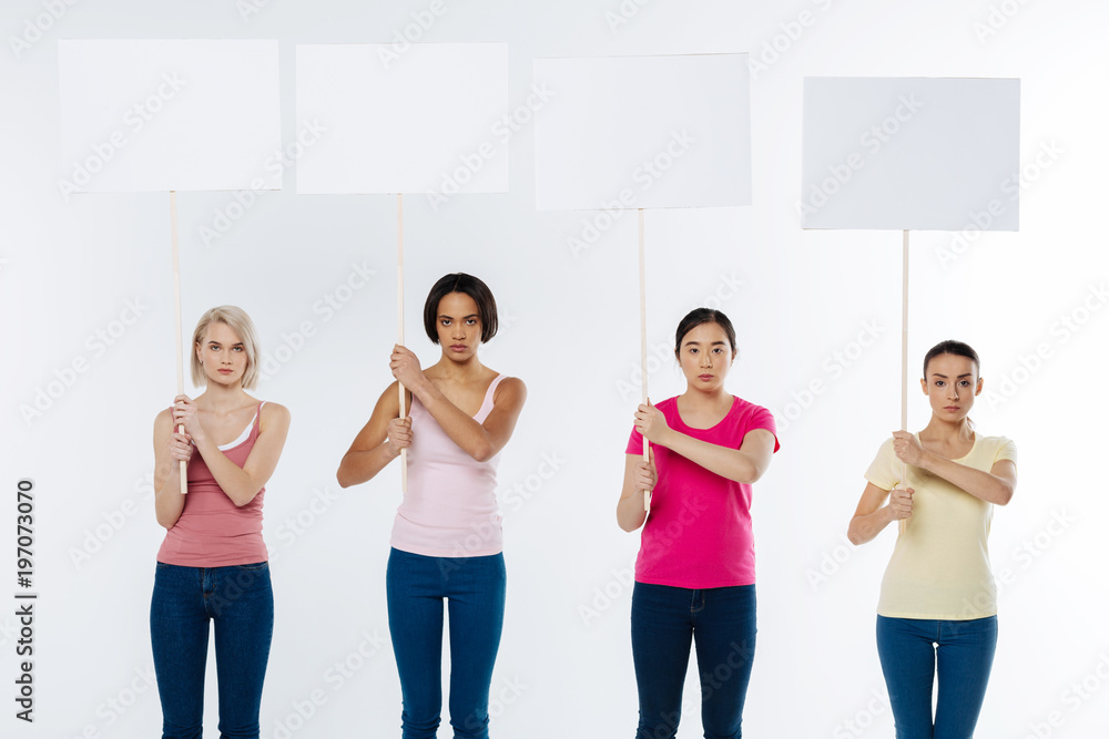 Fototapeta premium Serious issue. Smart pleasant attractive women looking at you and holding signs while being serious about social issues