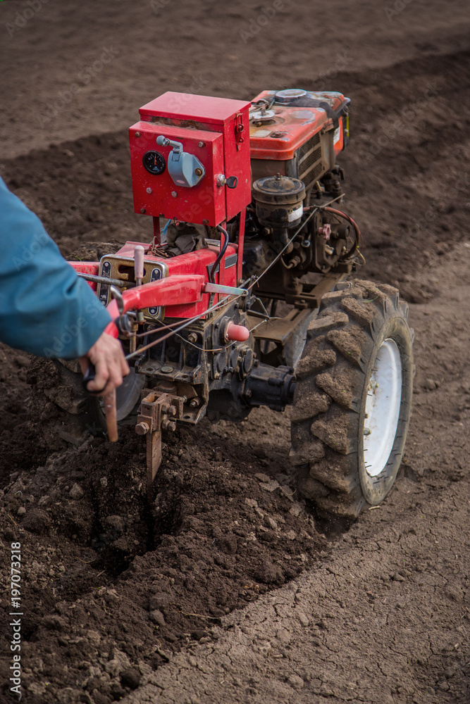 Farmer plows the land with a cultivator, preparing it for planting vegetables Farmer plows the land with a cultivator, preparing it for planting vegetables