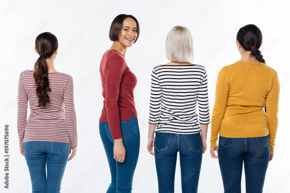 Obraz premium Social project. Happy positive young woman standing among her friends and turning to you while smiling