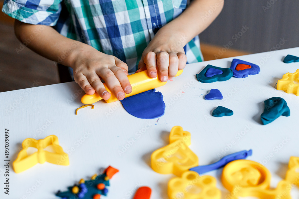 Child hands playing with colorful clay. Homemade plastiline. Plasticine.  play dough. Girl molding modeling clay. Homemade clay. Stock Photo