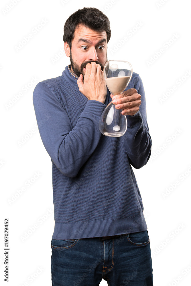 Handsome brunette man with beard holding a sand clock on white background Handsome brunette man with beard holding a sand clock on white background