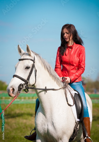  Woman sitting horse. Day. Full height. Red leather jacket