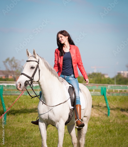  Woman sitting horse. Day. Full height. Red leather jacket