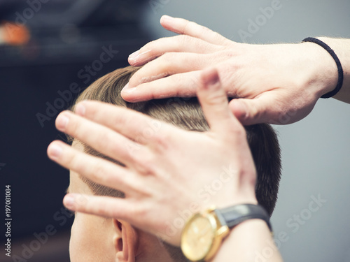 Barber making hairstyle to a boy using hair gel. © Artem