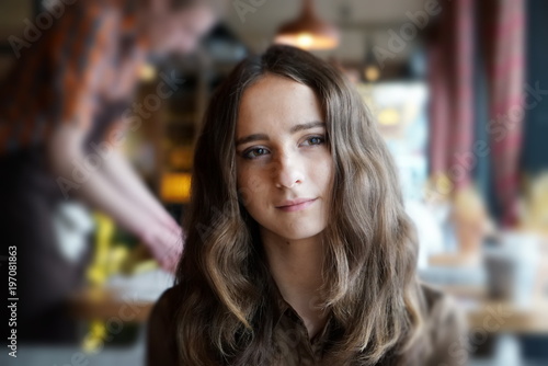 Thoughtful beautiful girl with long brown hair in a cafe