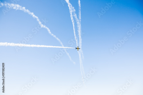 A group of professional pilots of military aircraft of fighters on a sunny clear day shows tricks in the blue sky, leaving beautiful traces of clouds scattered in different directions. © Timur Abasov