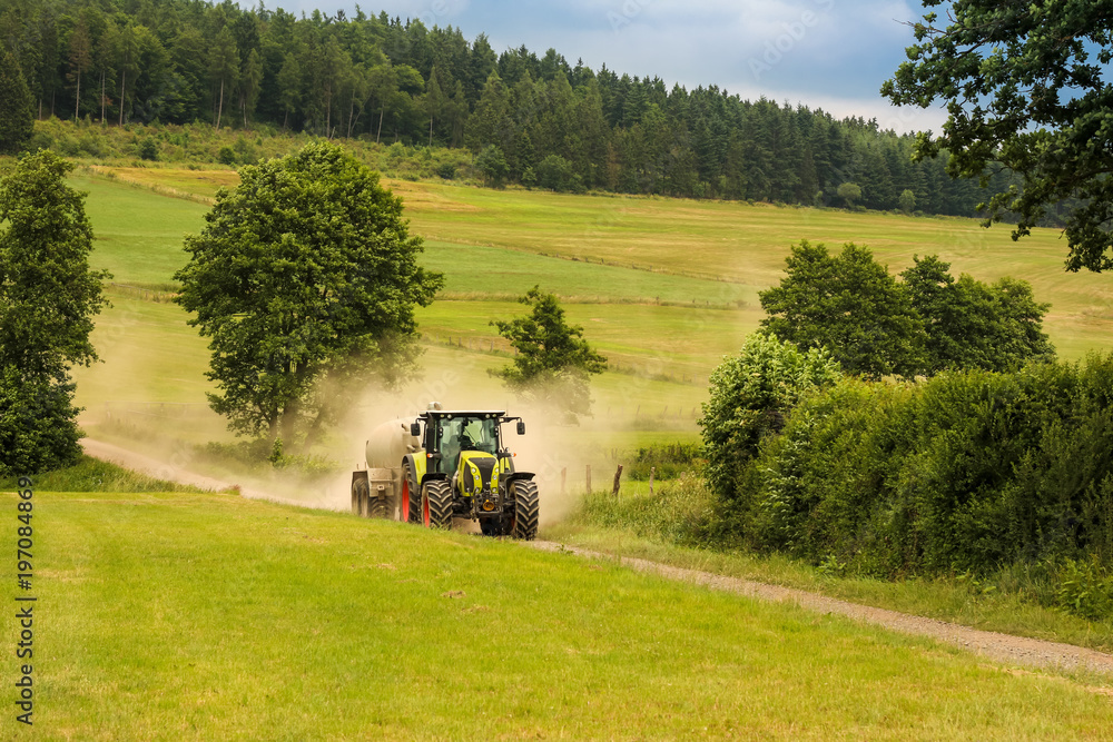 Fototapeta premium Traktor auf Feldweg an staubigen Sommertag
