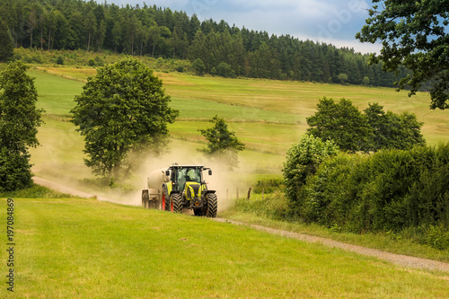 Traktor auf Feldweg an staubigen Sommertag