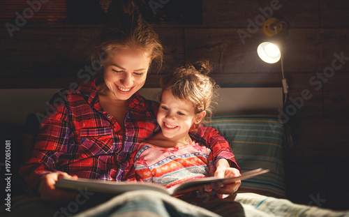 mother and child reading book in bed before going to sleep . photo