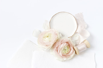 Feminine wedding, birthday desktop mock-up scene. Porcelain plate, blank craft paper greeting cards, silk ribbon, blush pink Persian buttercup flowers. White table background. Flat lay, top view.