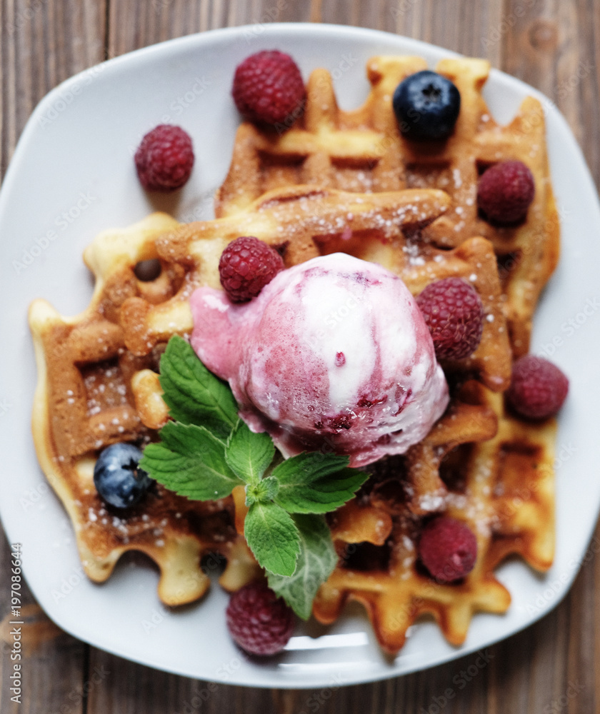 Plate of belgian waffles with ice cream and fresh berries - raspberries and blueberries.top view close-up. Plate of belgian waffles with ice cream and fresh berries - raspberries and blueberries.top view close-up.