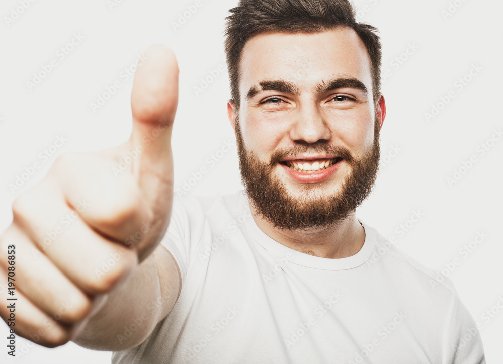 Portrait of a cheerful young bearded man showing okay gesture isolated on the white background Portrait of a cheerful young bearded man showing okay gesture isolated on the white background