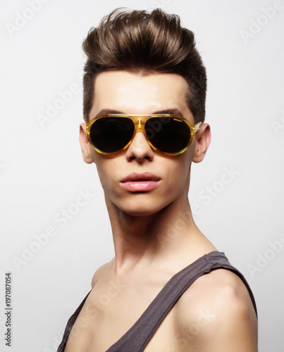 Sexy young man in fashion style wearing sunglasses. Male model.