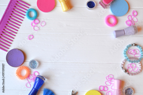 Colorful and bright cosmetics. Beauty care tools. Beauty salon. Girl's paradise. Nail polishes, sequins, pink hair bands and comb on the white wooden desk. Bright still life of beauty instruments.