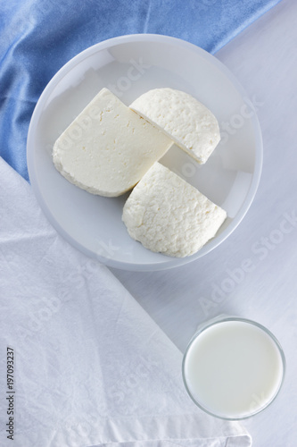 Cheese, cheese on a white plate, a glass of yogurt, minimalism, top view, copy space, dairy products on a white napkin, blue cloth, cheese pattern, French breakfast, white cheese on a white background