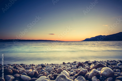 Fototapeta Naklejka Na Ścianę i Meble -  Beautiful and colorful coastal sunset with island peninsula. Pebble beach in Croatia, Europe. Adriatic sea.
