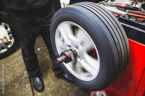 Mechanic aligning car tire at service