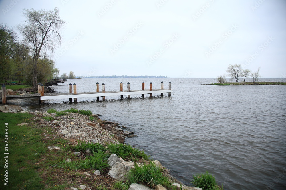 Fototapeta premium Dock and Lake - Wooden dock extends out into a waterway.