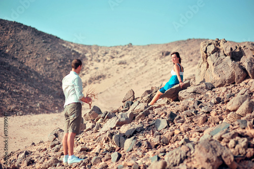 Happy young couple having fun in desert sand on vacation honeymoon travel holidays. Caucasian woman and man playing playful enjoying love on date. Multiracial couple